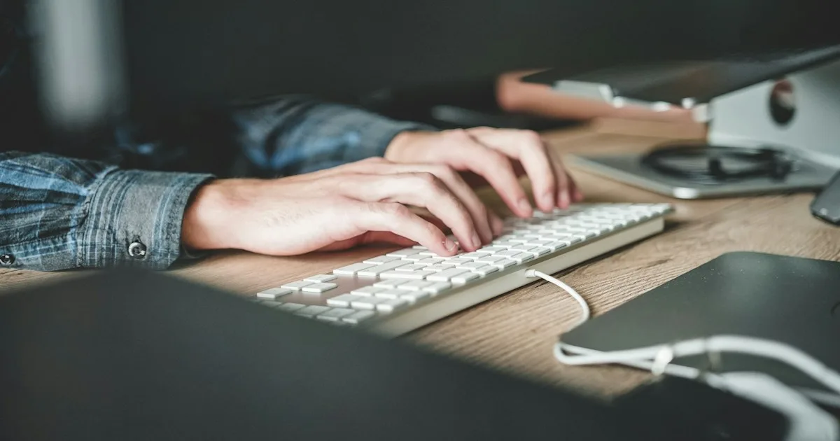 Person typing on a computer keyboard at a tidy ergonomic desk - KeyRiser