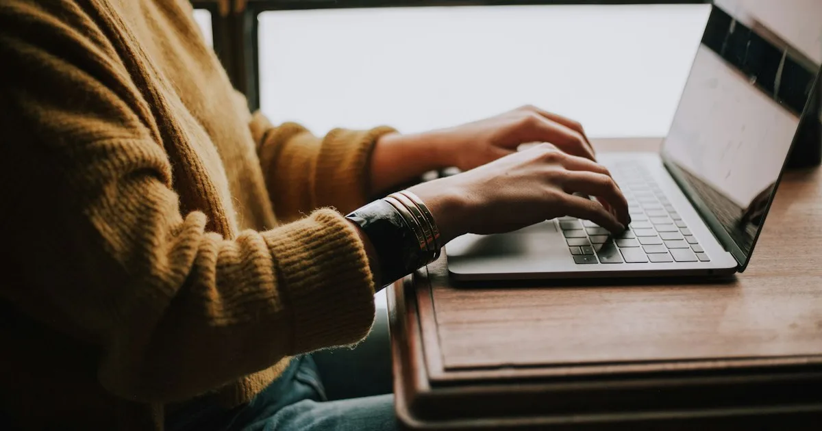 Hands typing on a flat low-profile keyboard on a desk - KeyRiser