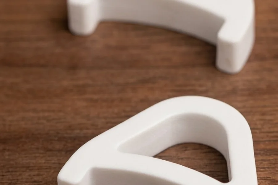 A close-up of a white KeyRiser piece clipped onto the rear edge of a keyboard, lifting it at an angle